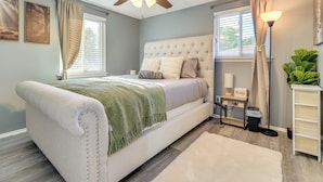 A bedroom with a bed, ceiling fan, bedside table, lamp, and a plant. - Westland Family Home w/ Deck & Fenced Yard (Westland)