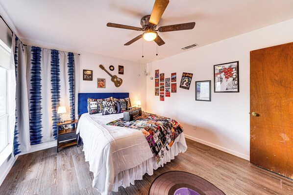 A bedroom with a bed, ceiling fan, wall decorations, and a wooden floor. - Unique & Stylish San Antonio Home w/ Deck! (San Antonio)