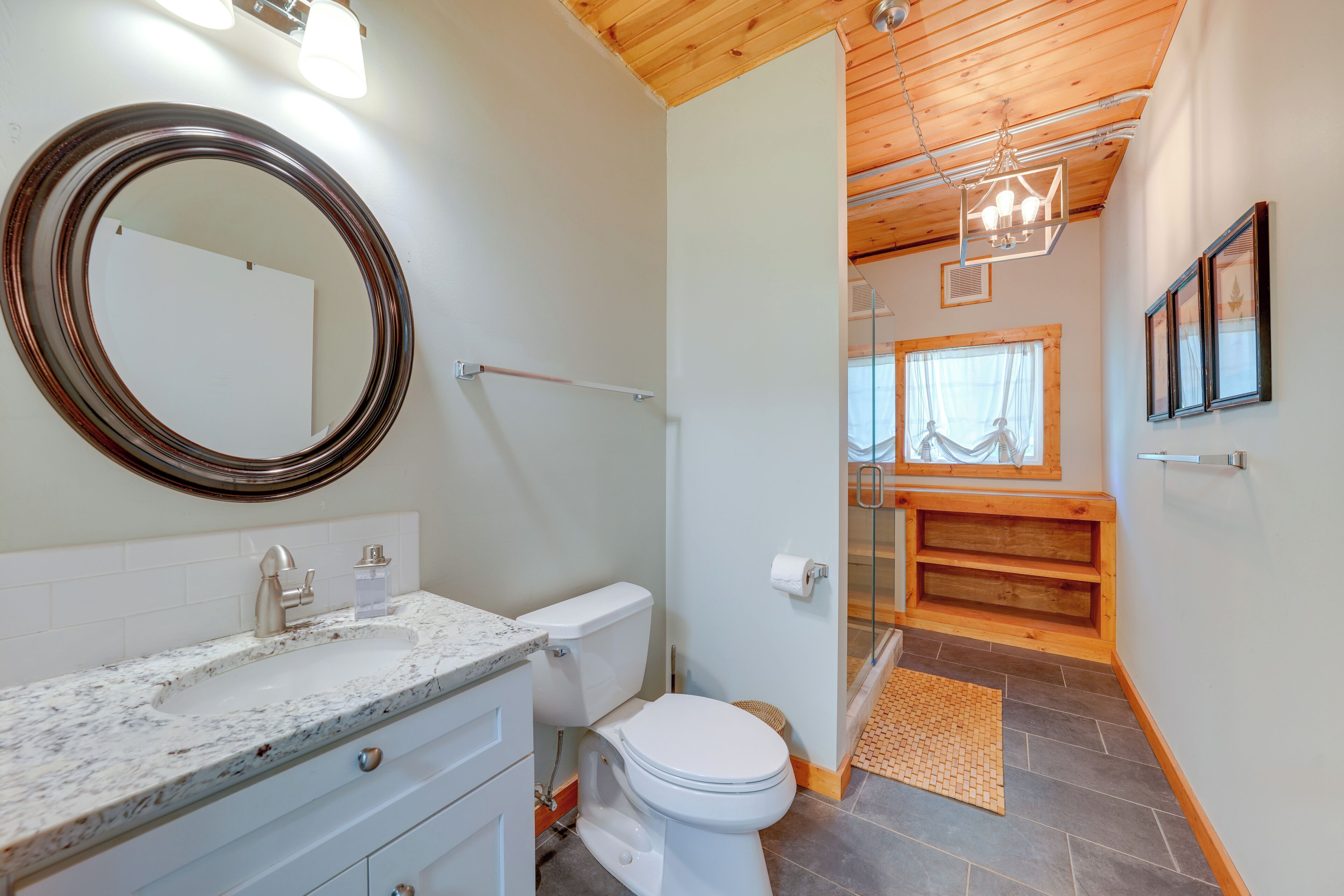 Une salle de bain avec un lavabo en marbre, des toilettes et une cabine de douche en bois.