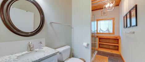 Une salle de bain avec un lavabo en marbre, des toilettes et une cabine de douche en bois.