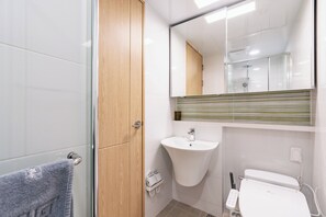Enjoy a refreshing shower in this bathroom featuring a glass shower enclosure, a sink with a mirror, and a toilet with a bidet attachment.