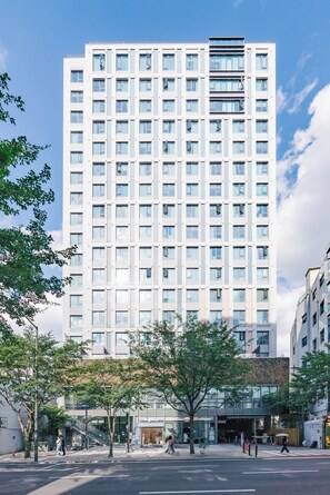 Experience the contemporary architecture of this high-rise building, featuring a grid of windows and central entrance.