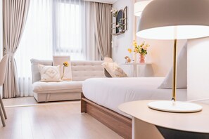 Relax in this serene bedroom with a large bed, sofa, and elegant bedside table.