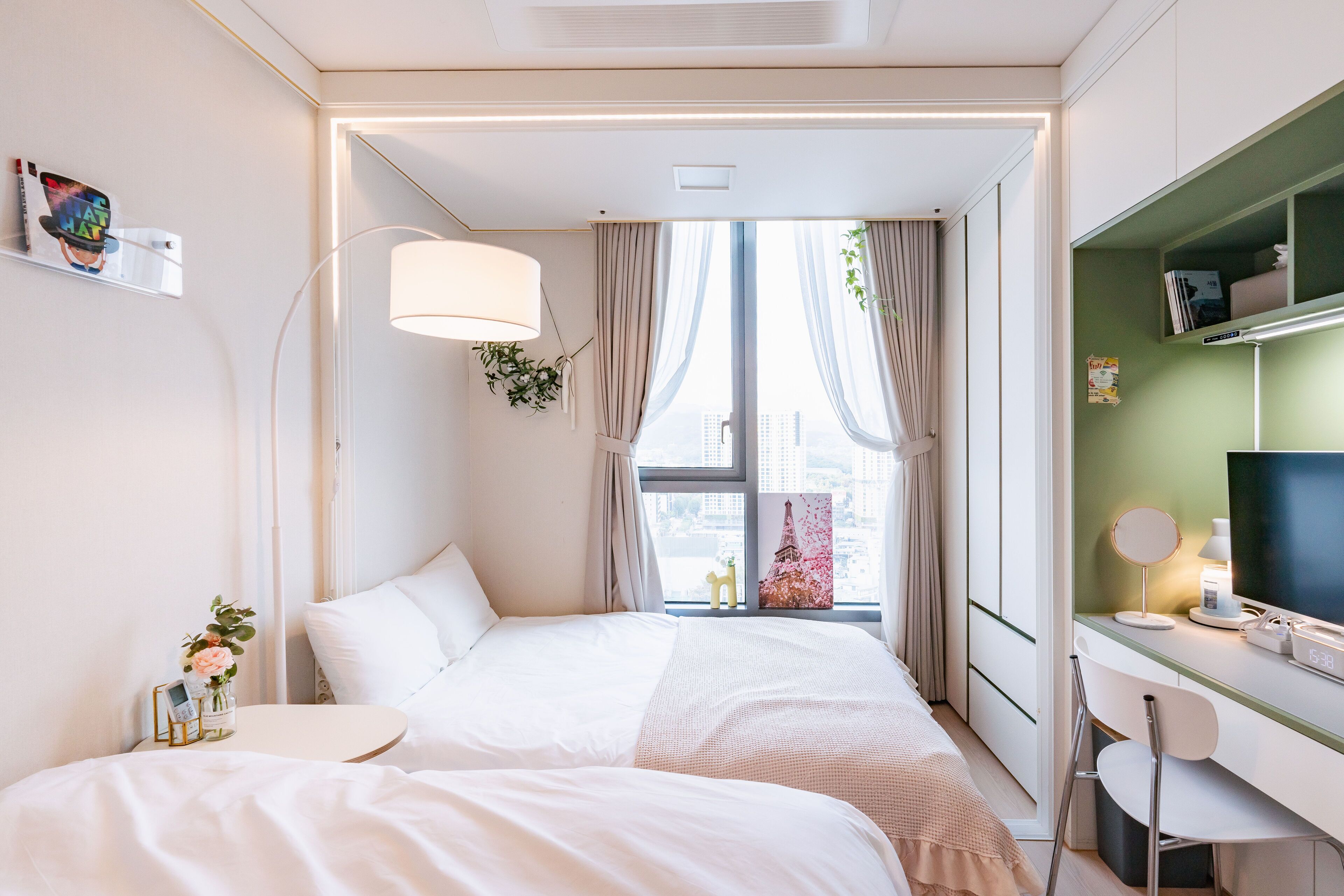 A modern hotel room with a bed, bedside table, and a desk with a chair.