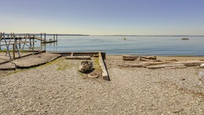 A pebbled beach with a wooden dock extending into calm waters.