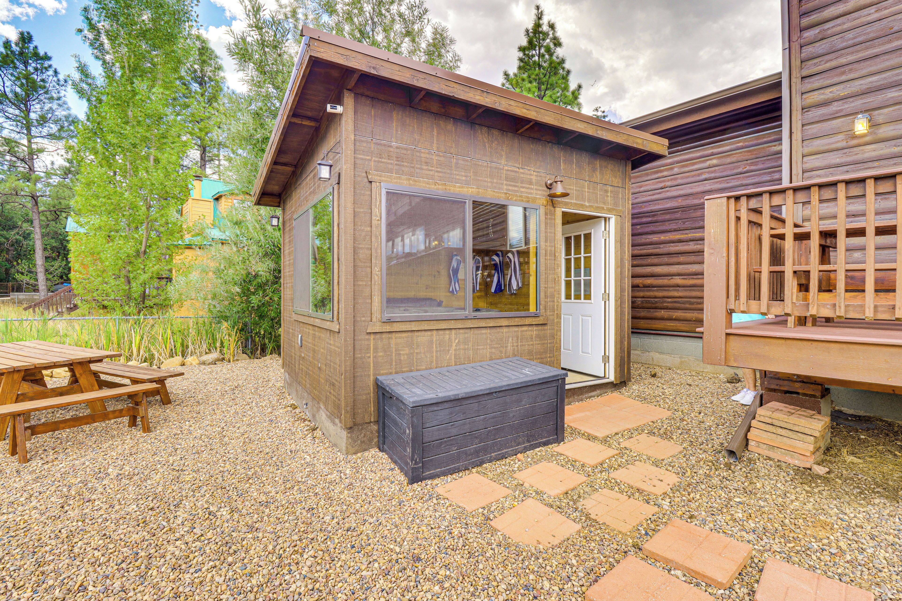 A wooden cabin with a large window, a bench, and a picnic table.