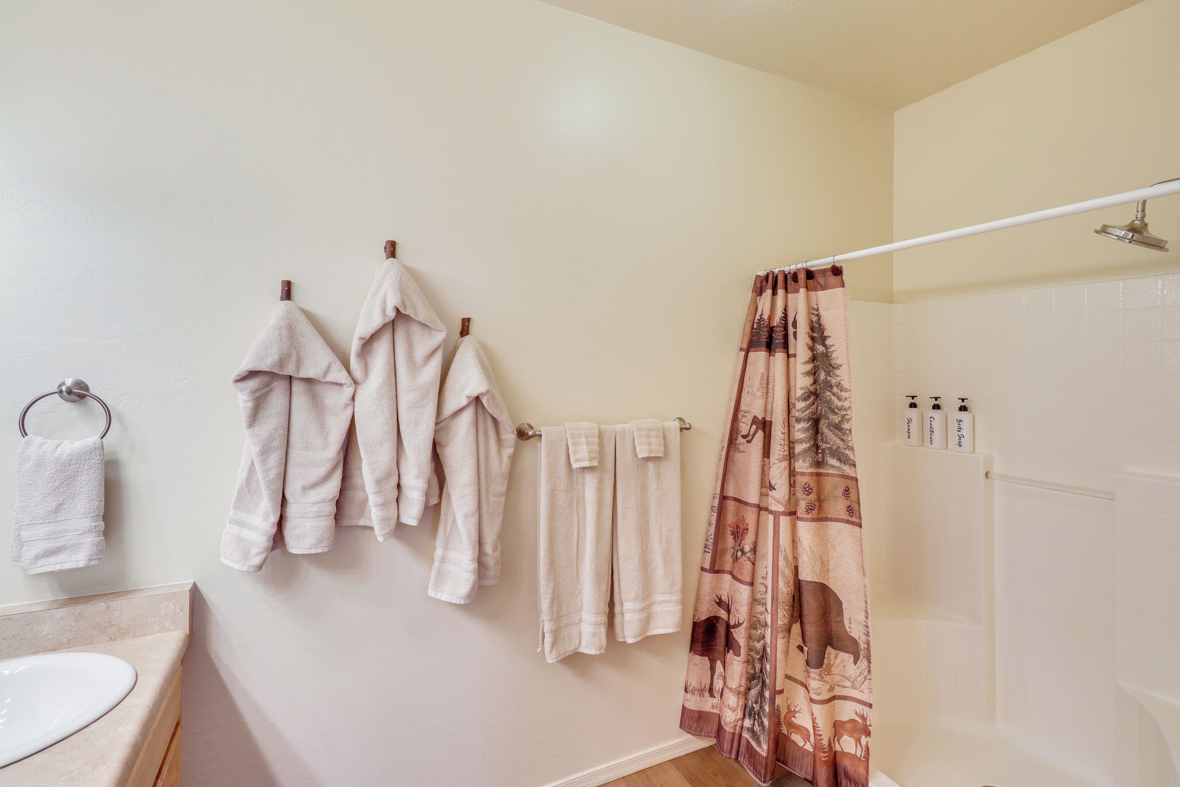 Une salle de bain avec un lavabo, plusieurs serviettes, un rideau de douche et des articles de toilette accrochés au mur.