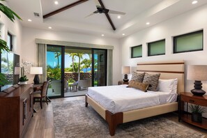 Relax in a serene space with a large bed, desk, and potted plant, offering a view of the outdoors.