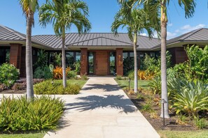 Stunning building with a central entrance, surrounded by palm trees and lush greenery.