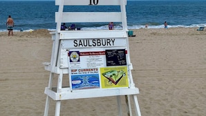 A beach lifeguard stand with the number 10, labeled 'SAULSBURY', and various safety and beach information signs.
