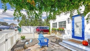 A house with a blue door, a red car parked in front, and a blue chair outside.