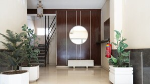 A modern lobby with a staircase, a round mirror, and potted plants. - LIV - Sunny Penthouse Near Acropolis (Athens)