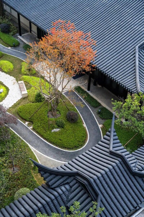 Un edificio tradicional con tejados curvos y un jardín ajardinado con un árbol.