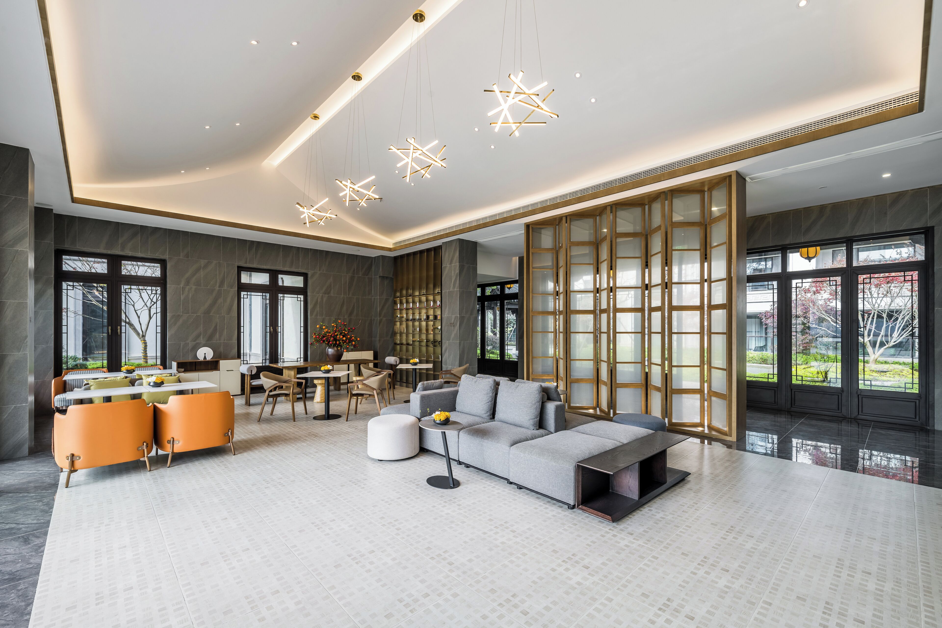 A spacious living area with a grey sofa, orange chairs, and a dining table.