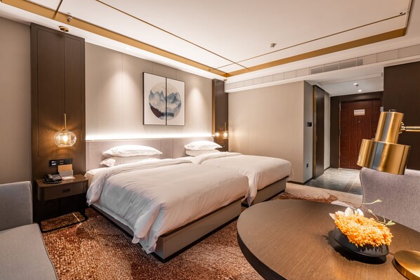 A modern hotel room with a large bed, bedside tables, a round coffee table with flowers, and a painting on the wall. - Poltton Century Hotel Changtai Taoli  (Zhangzhou)