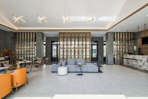 A modern living room with a sectional sofa, a dining area, and a kitchen area with a TV. - Poltton Century Hotel (Changtai Taoli Chunfeng Branch) (Zhangzhou)