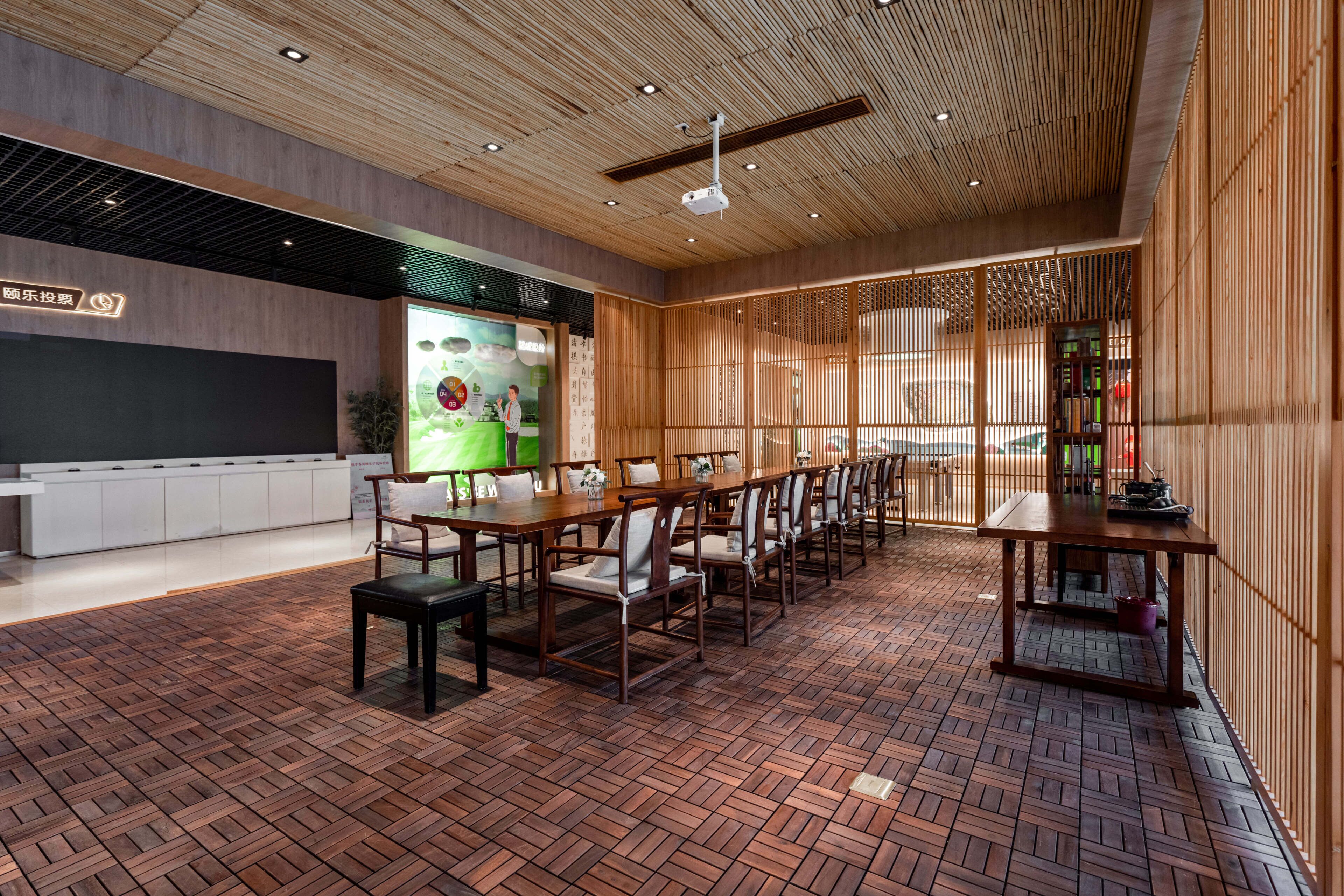 Une salle de conférence moderne avec un plafond en bois, un grand écran et un sol décoré d’un motif en briques.