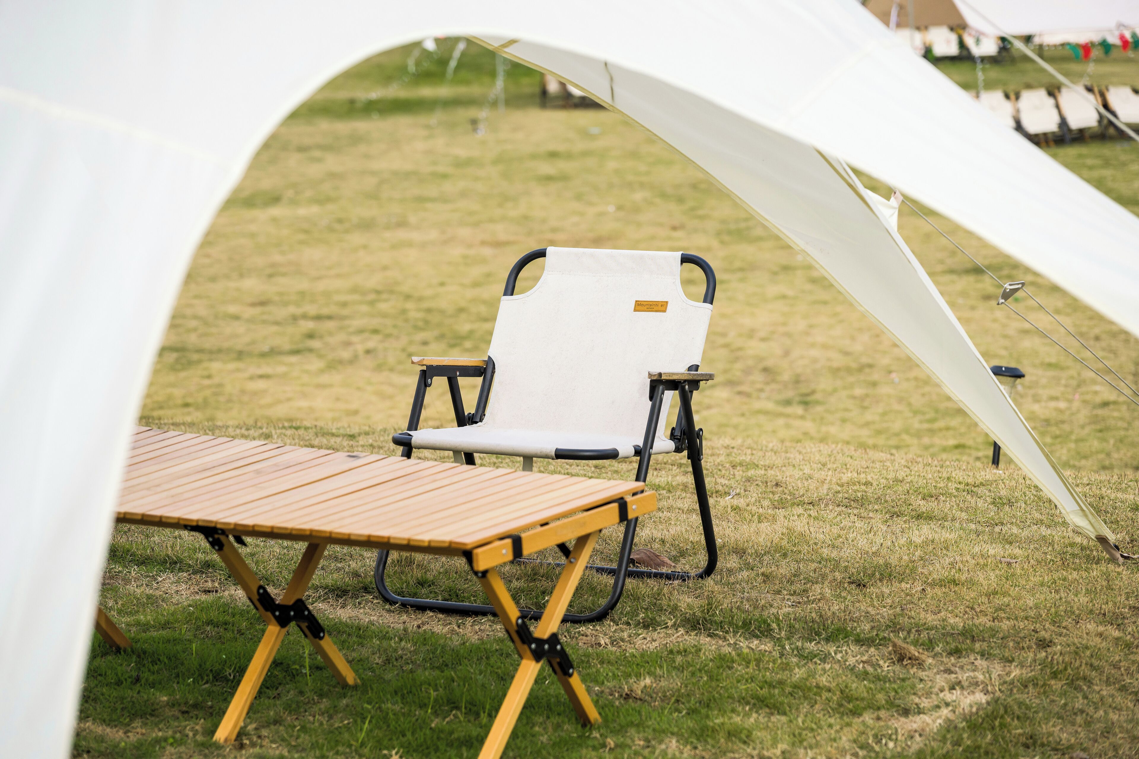 Un campamento con una tienda de campaña, una mesa de madera y una sola silla.