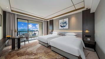 Una habitación de hotel moderna con dos camas, un escritorio y vista al mar.