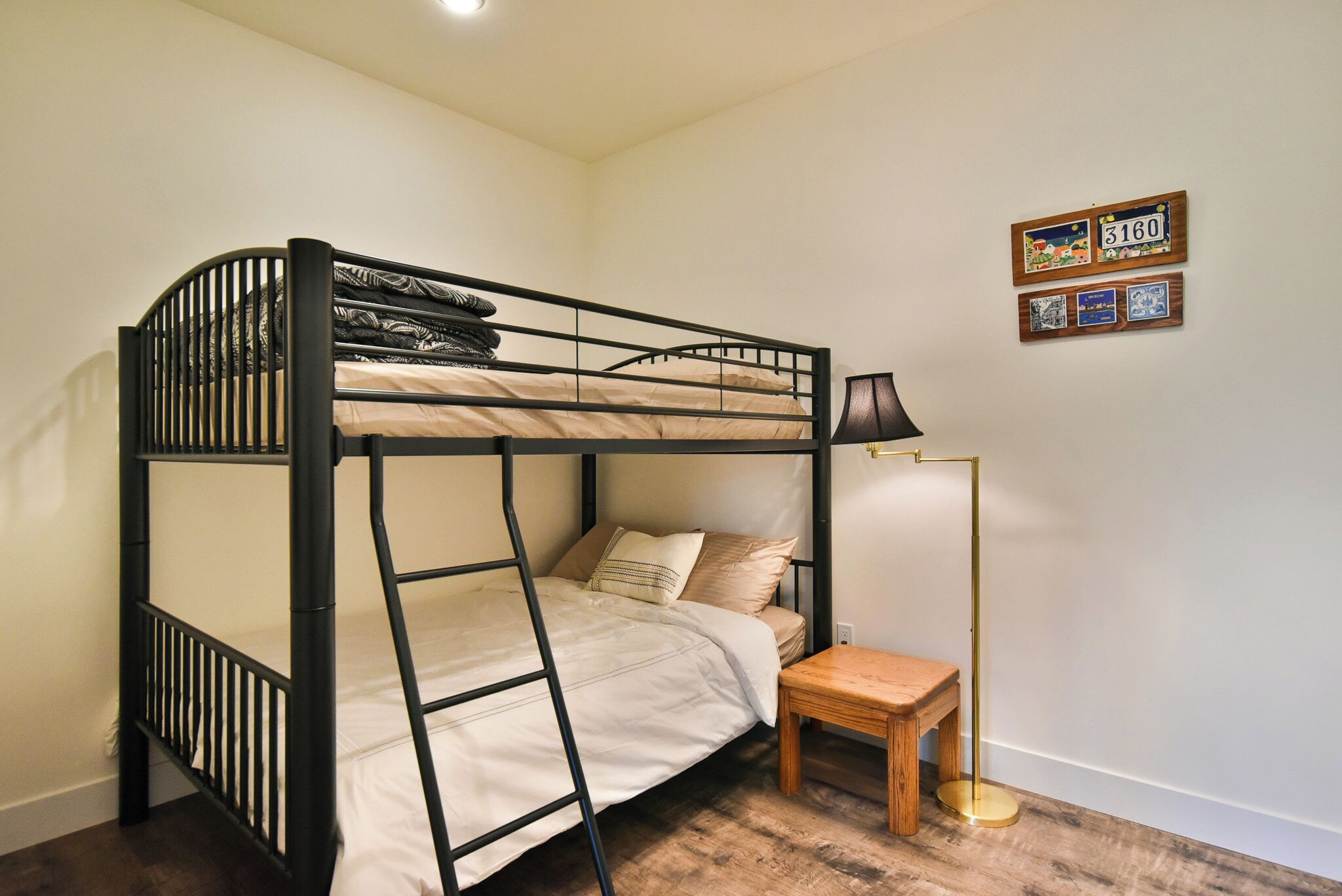 Uma cama beliche com escada, uma mesa de cabeceira, um abajur e um quadro fixado na parede.
