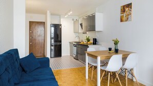 Una cocina moderna con armarios blancos, un refrigerador negro y una mesa de comedor de madera con sillas blancas.