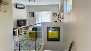 A spacious living area with a glass railing, a sofa, and a framed award on the wall. - LUXURIOUS TWO-STORY SELF-CATERING RETREAT IN THE HEART OF THE CAPE WINELANDS 
 (Somerset West)