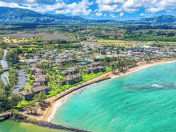 A coastal resort with beachfront villas, a marina, and a mountain backdrop. - Pono Kai Resort J201, AC, 2nd Floor, Walk to Beach (Kapaa)