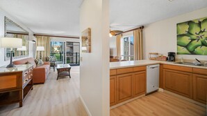 A modern kitchen with wooden cabinets, a dishwasher, and a large window. - Pono Kai Resort J201, 2nd Floor, Walk to Beach (Kapaa)