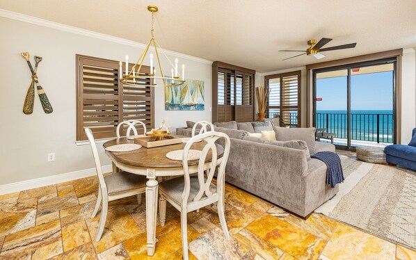 A spacious living area with a dining table, a sofa, and a view of the ocean.