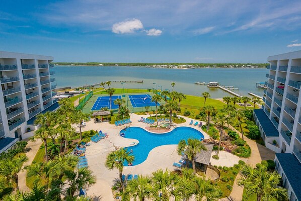 A resort with a central swimming pool, tennis courts, and a view of the water. - Gulf Shores Surf & Racquet 801a 3 Bedroom Condo (Gulf Shores)