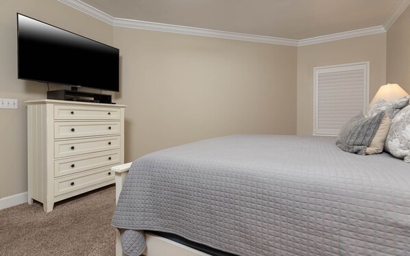 A bedroom with a bed, a dresser, a television, and a window with blinds. - Phoenix Ix 1106 2 Bedroom Condo (Orange Beach)