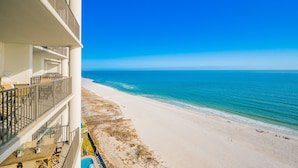 Un hôtel en bord de mer, doté de balcons avec vue sur l’océan, d’une piscine et d’une plage de sable.