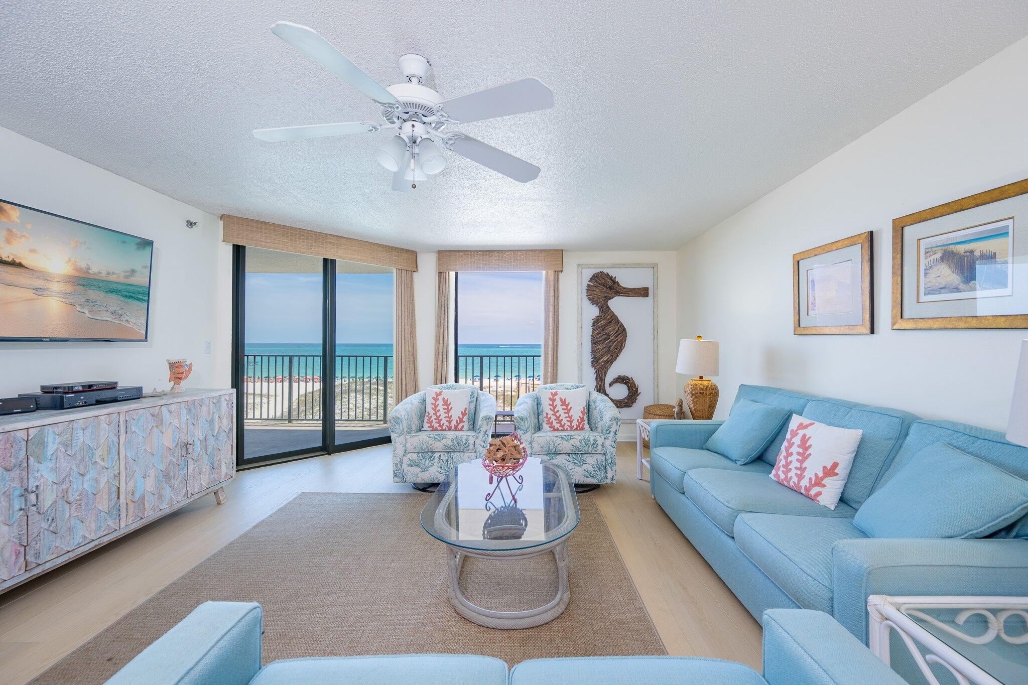 A living room with a sofa, a coffee table, a TV, and a ceiling fan.