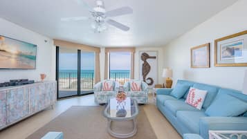 A living room with a sofa, a coffee table, a TV, and a ceiling fan.