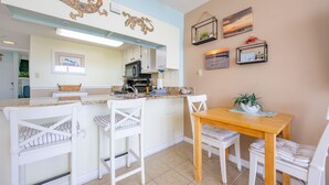A kitchen with white cabinetry, a wooden dining table, and white chairs. - Gulf Shores Surf & Racquet 612a 1 Bedroom Condo (Gulf Shores)