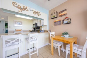Una cocina con armarios blancos, una mesa de comedor de madera y sillas blancas.
