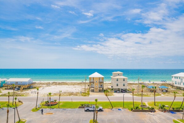 Un hotel frente a la playa con estacionamiento, playa y vista despejada al océano.