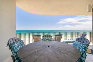 A round table with chairs, a view of the beach, and a curved awning. - Phoenix Ix 707 2 Bedroom Condo (Orange Beach)