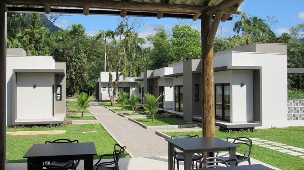 A modern outdoor area with a covered seating area and a pathway leading to multiple single-story buildings. - Vila do Porto Morretes (Morretes)