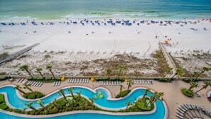 Ovenudblik over en strandresort med swimmingpool, strandparasoller og liggestole.