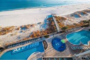 A beachside resort with a swimming pool, lounge chairs, and a lifeguard tower. - The Oasis 711 Formerly Phoenix West Ii 711 4 Bedroom Condo (Orange Beach)