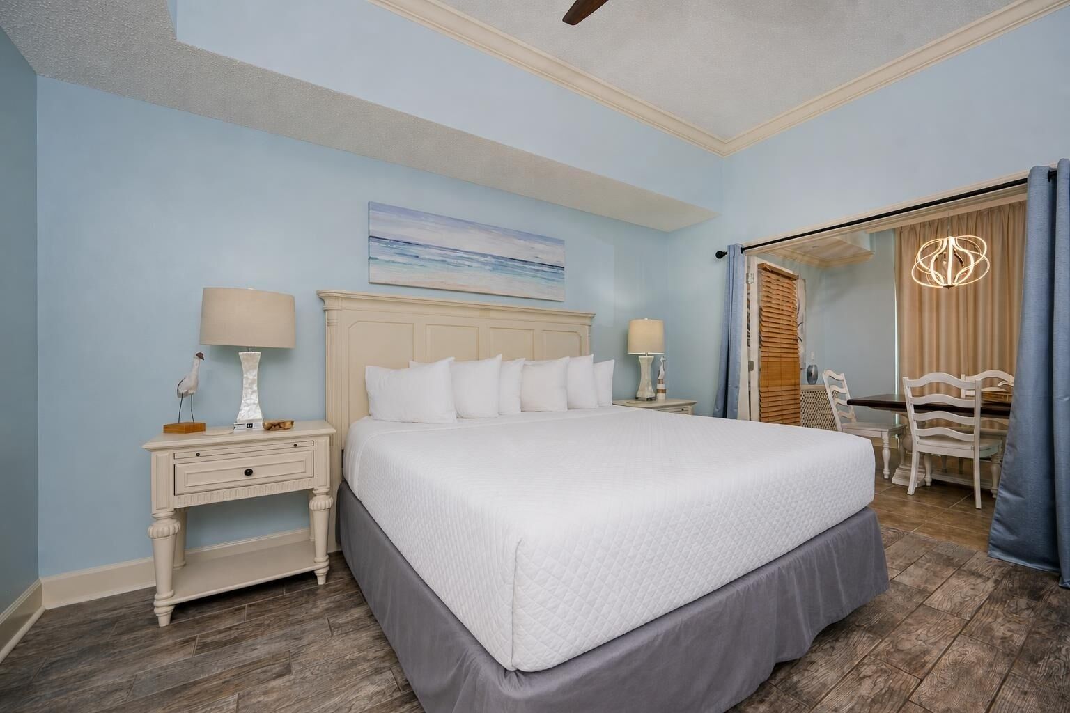 A bedroom with a large bed, two bedside tables, a nightstand, a chair, and a dining table.