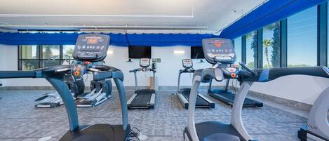 A gym with treadmills, stationary bikes, and a weight bench.
