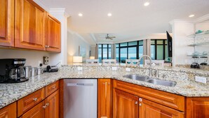 Una cocina con encimeras de granito, gabinetes de madera, lavavajillas y un amplio ventanal con vistas.