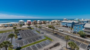 A coastal hotel with a parking lot, beach view, and several buildings with different architectural styles. - Gulf Shores Surf & Racquet 605a 1 Bedroom Condo (Gulf Shores)