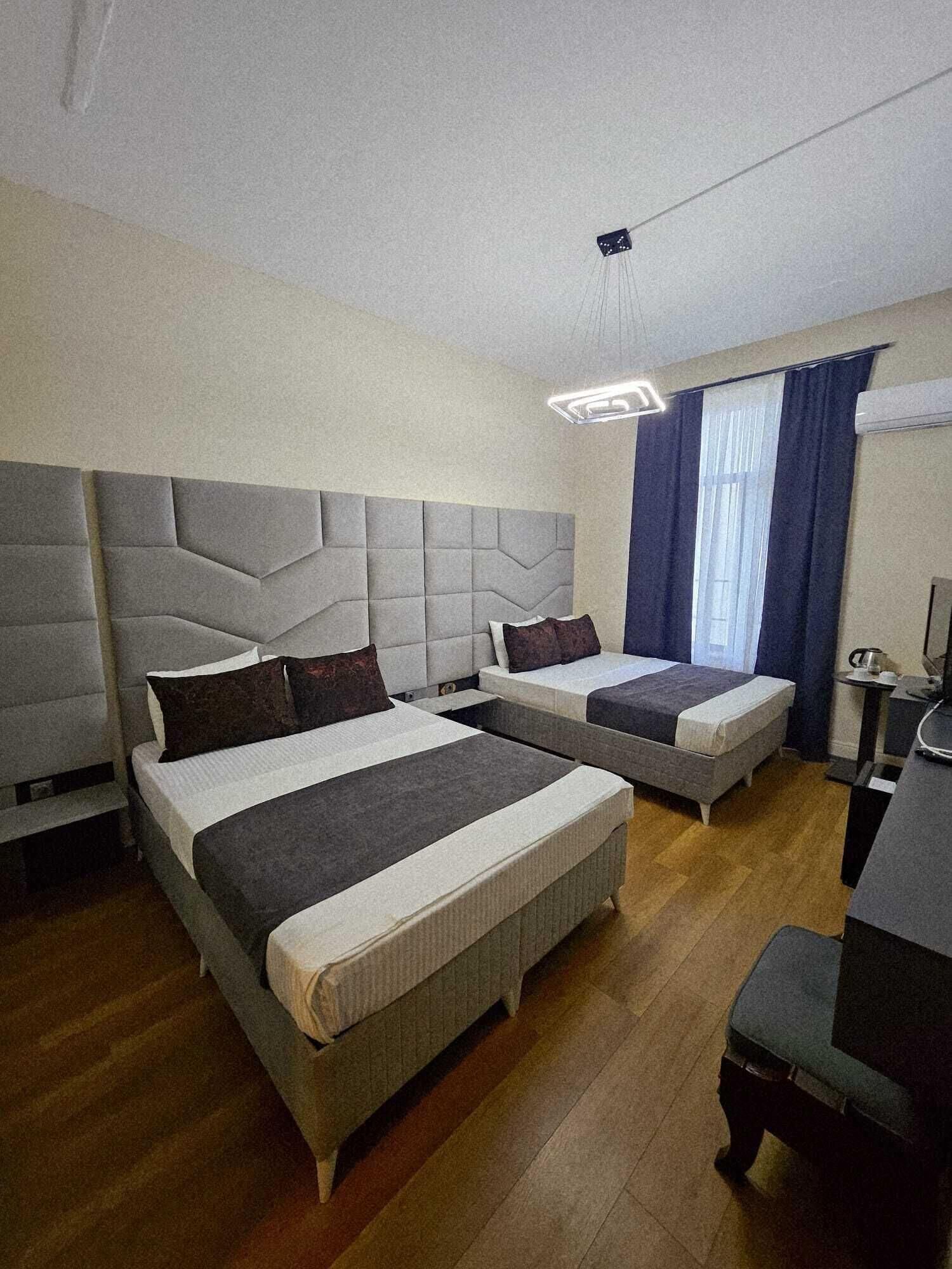 A hotel room with two beds, a desk, and a chair.