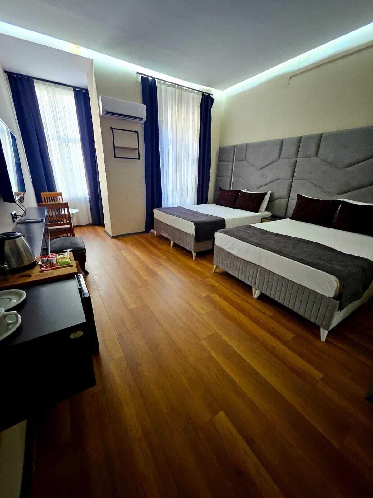 A hotel room with a bed, a desk, a chair, and a small table.