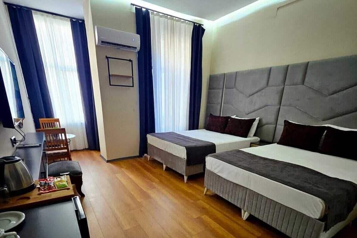 A hotel room with a bed, a desk, a chair, and a small table.