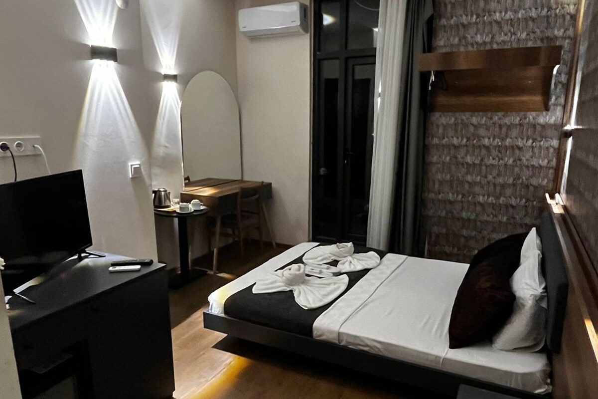 Una habitación de hotel moderna con cama, escritorio, silla y televisor.