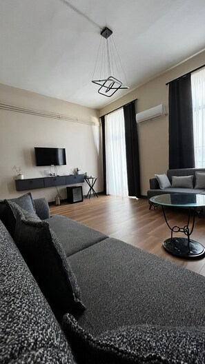 A modern living room with a sofa, a coffee table, a TV, and a dining area. - Taxim 34 (Istanbul)